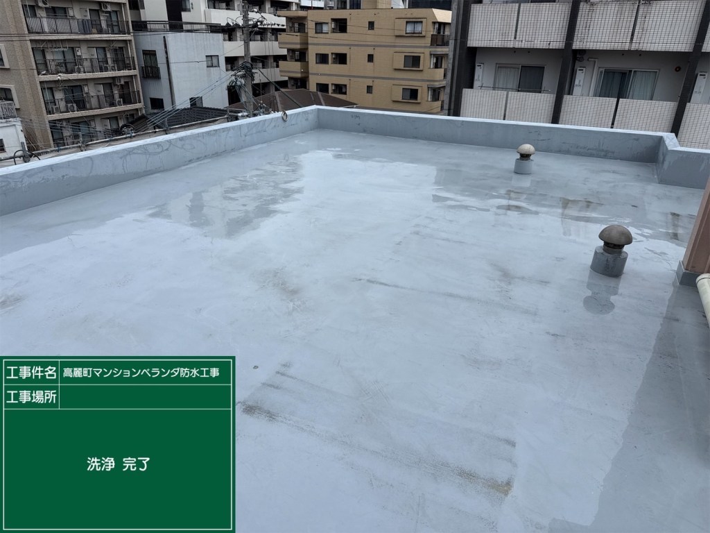 防水工事が完了した建物の屋上の画像。床は灰色で滑らかで、左右に小さな換気口が見える。周囲には高層ビルが立ち並ぶ。