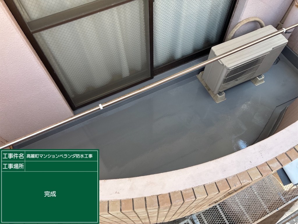 ベランダの防水工事が完了した様子を示す画像。灰色の床とエアコンが設置されている。