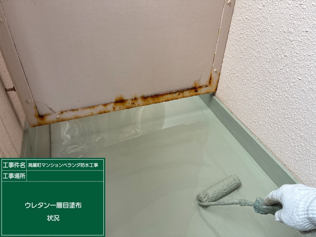 防水工事中の様子。ローラーでウレタン一層目の塗布を行っている。水たまりのある床と鉄板の上に塗料が塗られている。